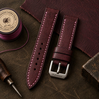 Wichtelmänner Burgundy full-grain leather watch strap with contrast stitching, flat lay on a leather workbench